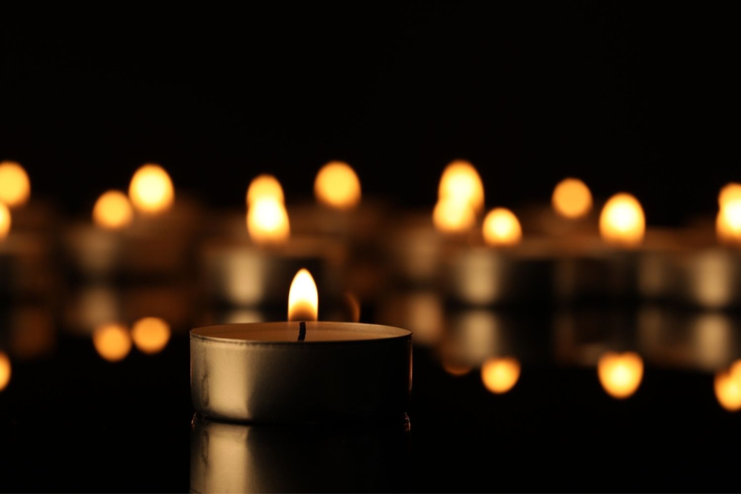 Burning candle on surface in darkness