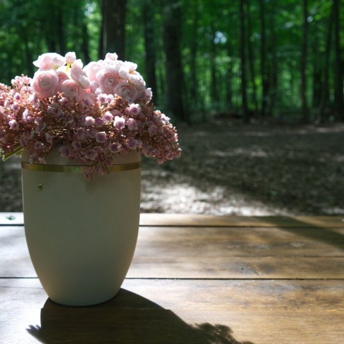 white funeral urn with soft pink flowers